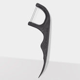 Close-up of The Humble Co. black dental floss pick displaying ergonomic curved handle with textured grip pattern and brand name embossed on side for secure handling
